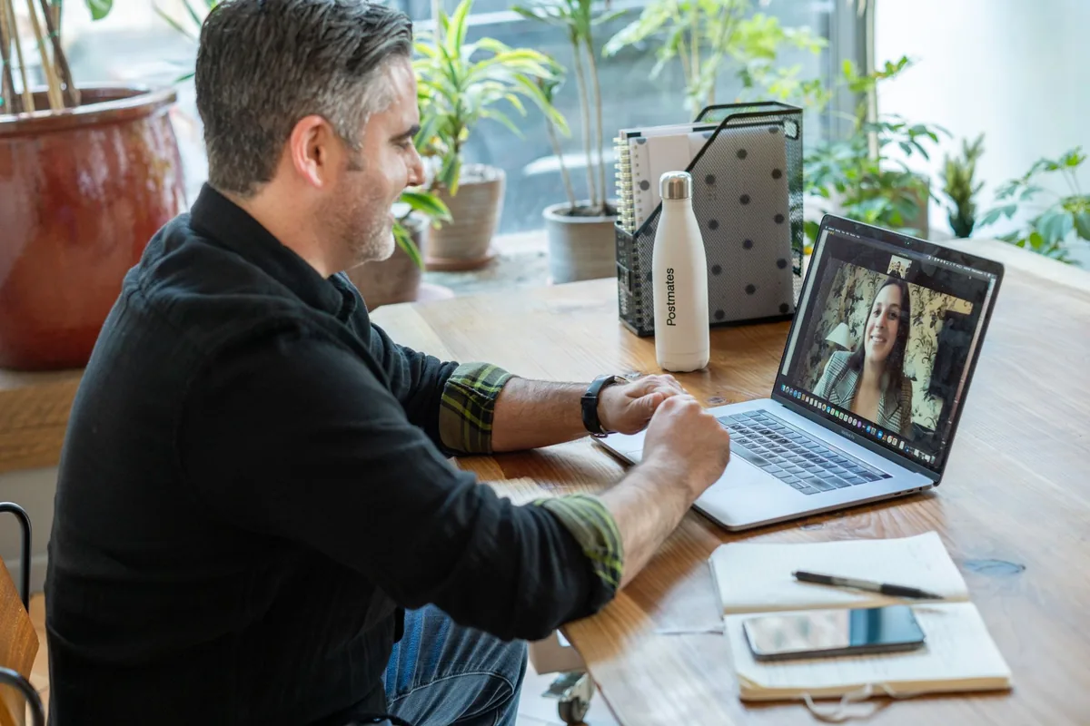 A man taking part in a coaching session over a video call on a laptop